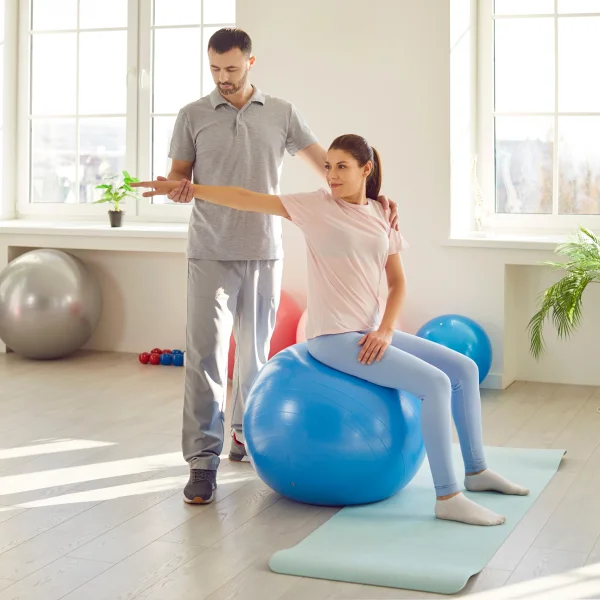 Un homme et une femme effectuent des exercices de physiothérapie sur un ballon d'exercice.