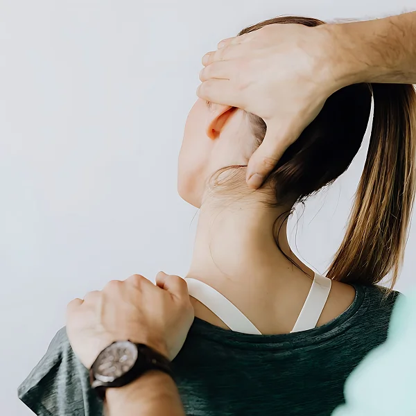 Une femme se fait examiner le cou par un chiropracteur dans un cadre de thérapie ostéopathique.