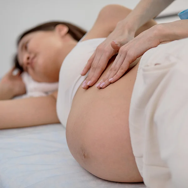 Femme allongée sur un lit, le ventre en contact avec le matelas, illustrant l'ostéopathie pendant la grossesse.
