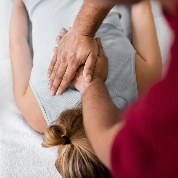 Une femme reçoit un massage thérapeutique d'un homme dans un cadre relaxant.