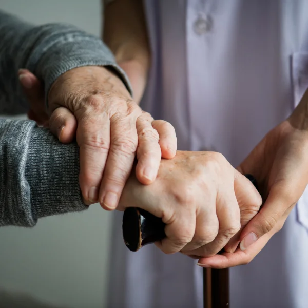 A nurse gently holds the hand of an elderly person, conveying care and support in a healthcare setting.